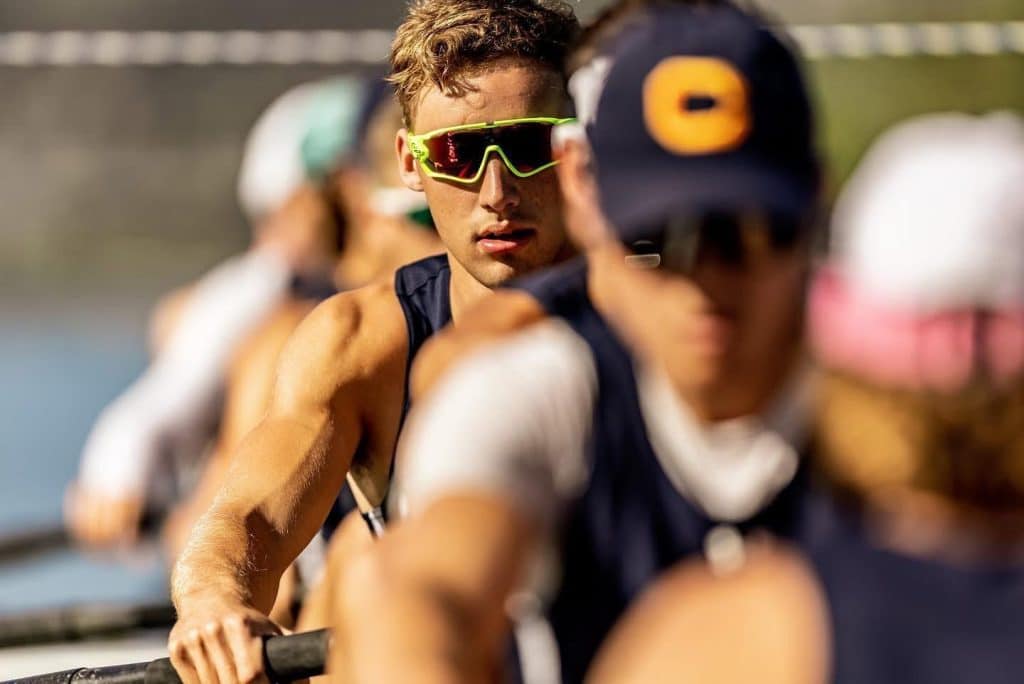 Rowing team member wearing sunglasses in action.